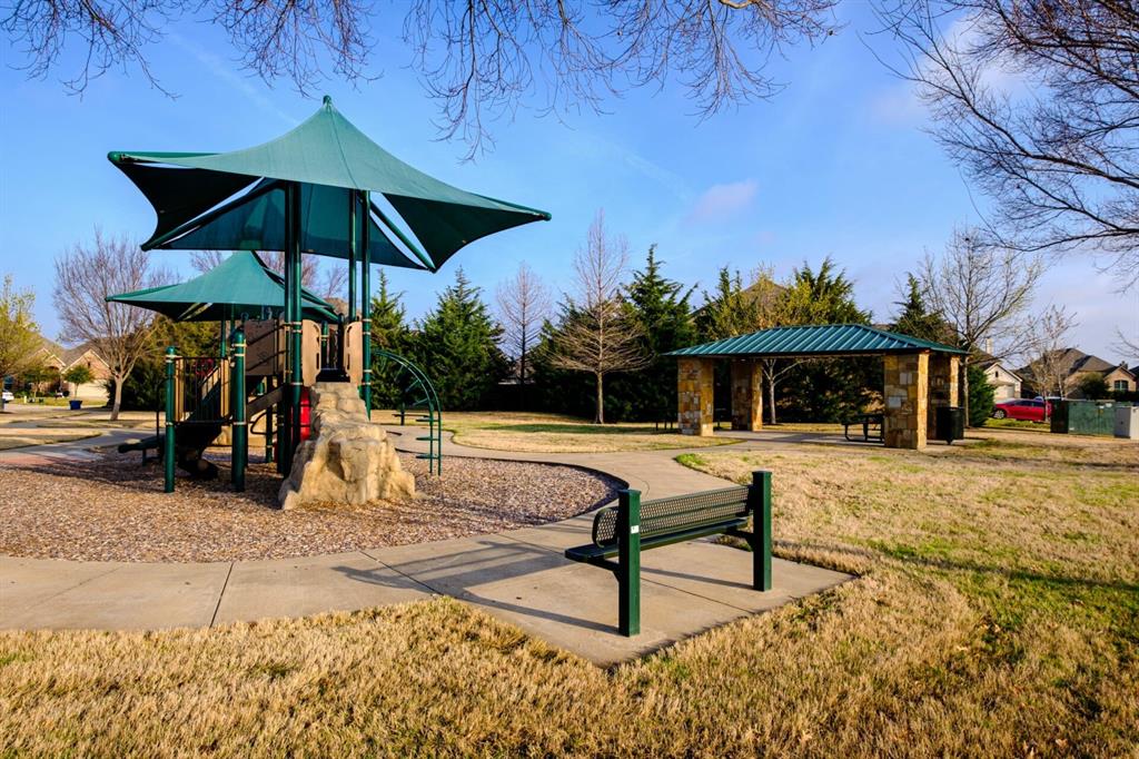 1016 Rio Bravo Drive Forney, TX 75126 - Photo 25 of 25 Community park area featuring a playground with shade canopies, a stone-columned pavilion, a paved pathway, and a green park bench
