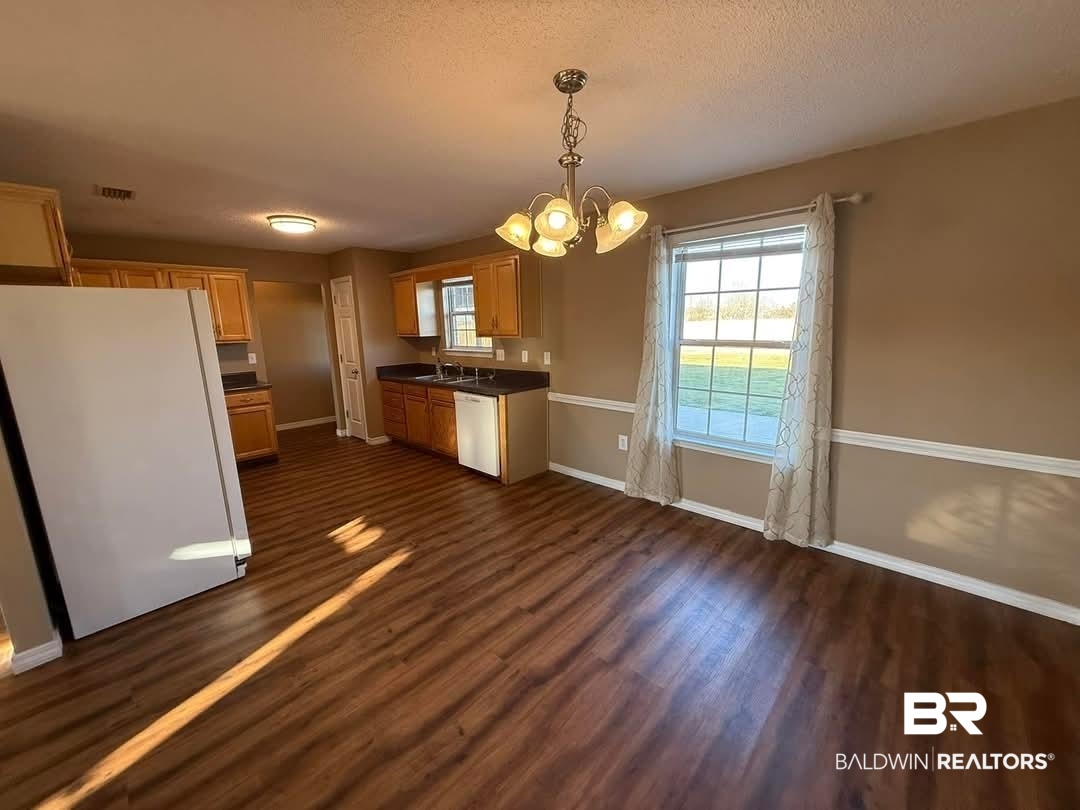 8912 Sherman Road Foley, AL 36535 - Photo 13 of 35 Kitchen with dark wood-style floors, decorative light fixtures, dark countertops, a sink, and white appliances