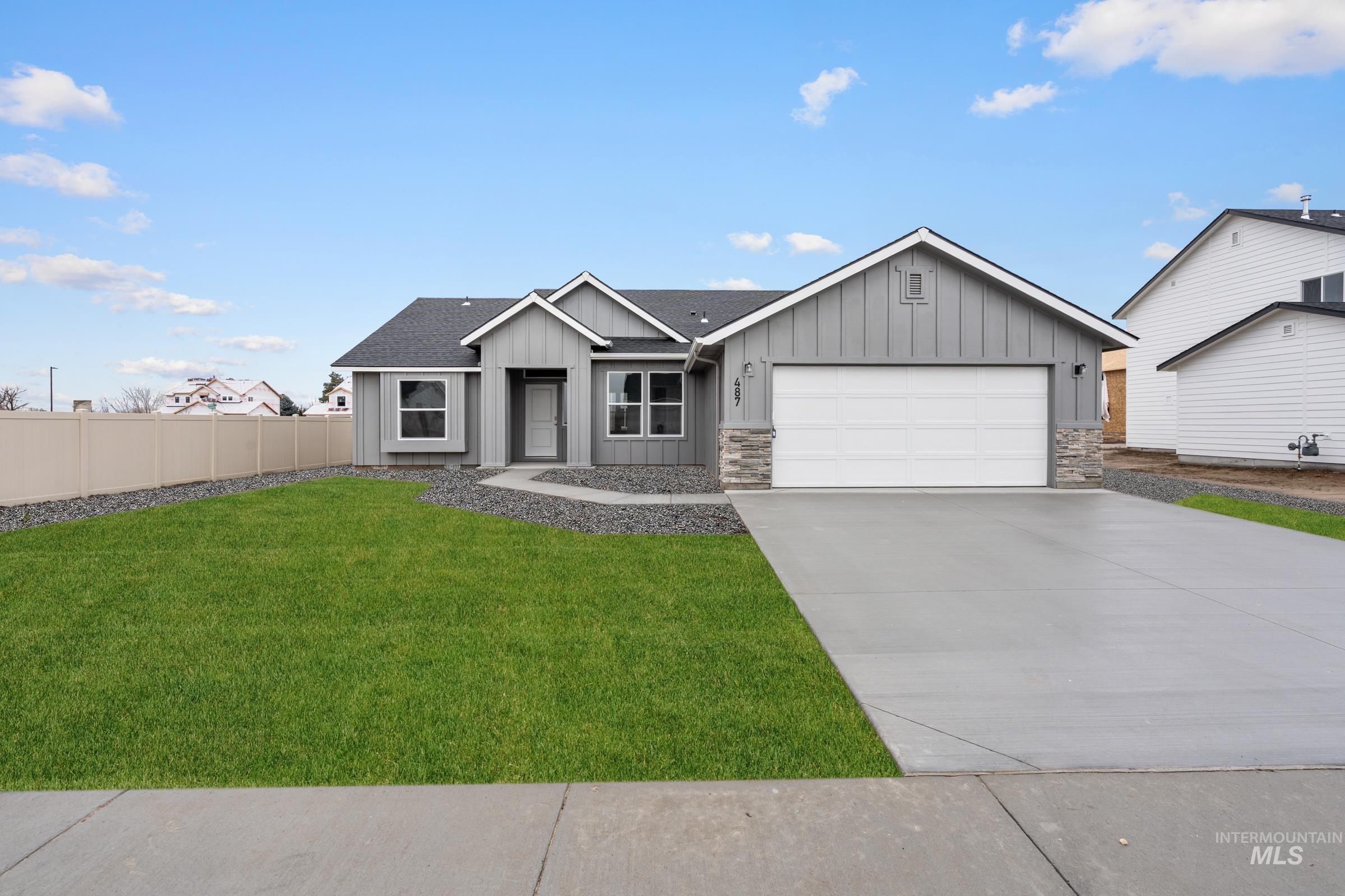 View of front facade featuring board and batten siding, a shingled roof, an attached garage, and driveway
