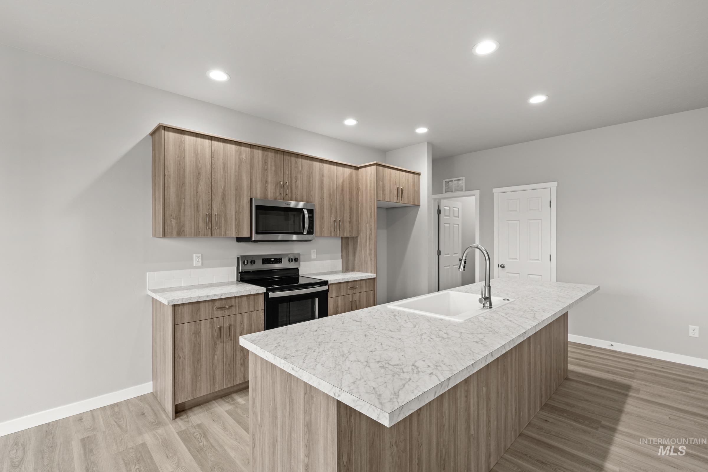 487 Hamlow Avenue Middleton, ID 83644 - Photo 5 of 19 Kitchen with range with electric stovetop, stainless steel microwave, a center island with sink, light countertops, and recessed lighting
