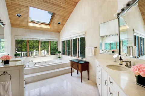 a spacious bathroom with a granite countertop tub next to a large window