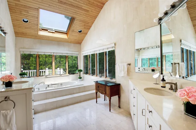 a spacious bathroom with a granite countertop tub next to a large window