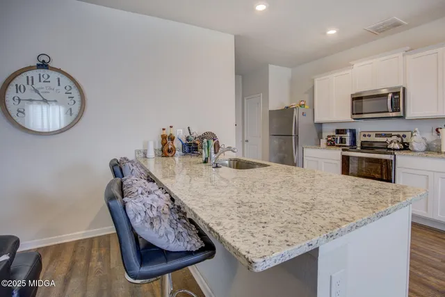 a kitchen with granite countertop a table chairs stove and cabinets