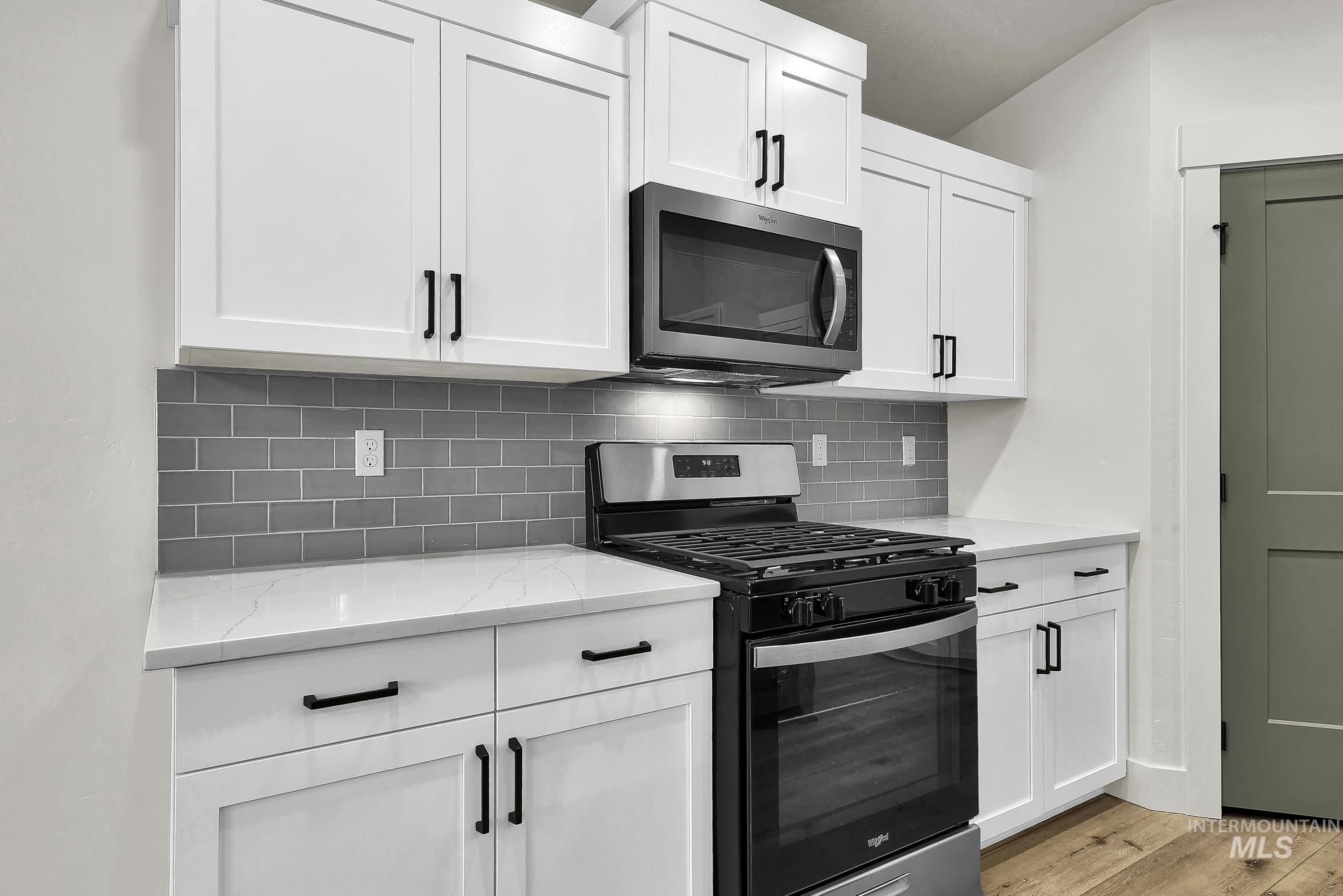 1130 Velvet Loop Wilder, ID 83676 - Photo 13 of 35 Kitchen featuring white shaker-style cabinetry with matte black hardware, stainless steel appliances, light-toned countertops, and gray subway tile backsplash