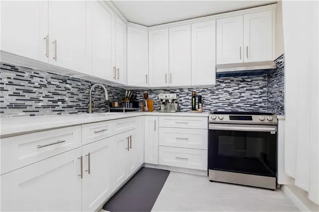 a kitchen with granite countertop white cabinets and white stainless steel appliances