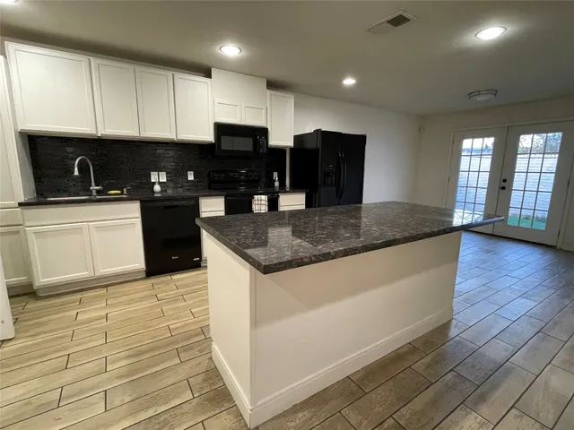 a kitchen with stainless steel appliances granite countertop a stove a sink and a microwave