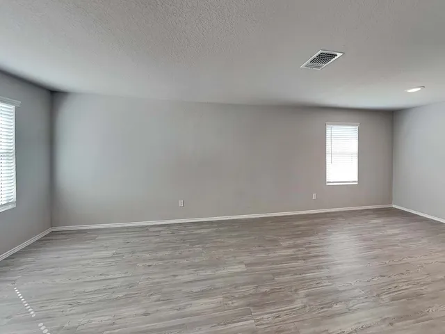 a view of an empty room with wooden floor and window