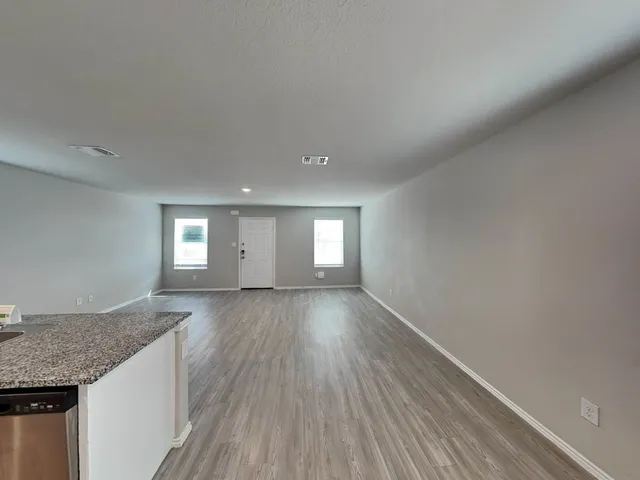 a view of an empty room with wooden floor and window