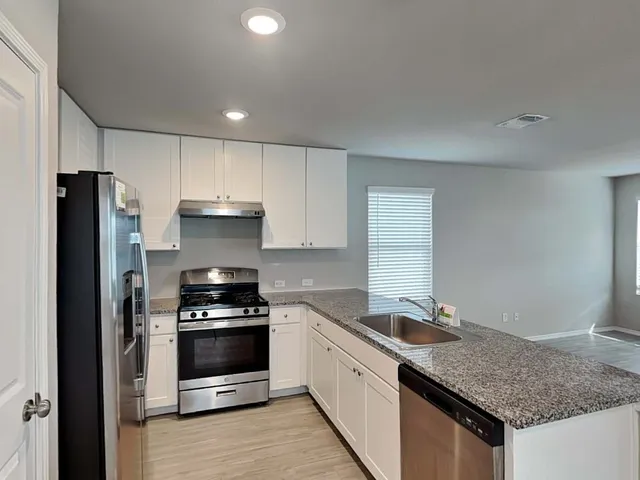 a kitchen with granite countertop a sink stove and refrigerator