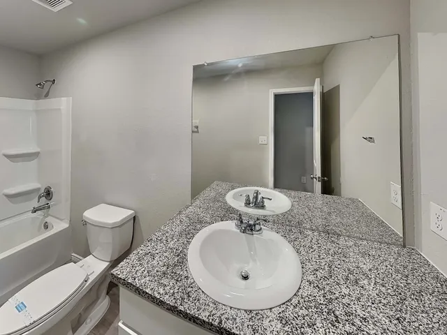 a bathroom with a granite countertop sink a toilet and a mirror