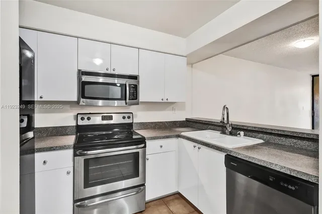 a kitchen with granite countertop a sink stainless steel appliances and white cabinets