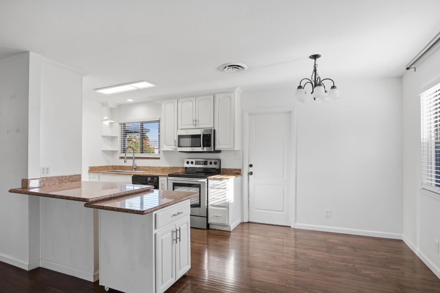 680 Sherri Way Turlock, CA 95382 - Photo 9 of 35 a kitchen with stainless steel appliances granite countertop a sink cabinets and wooden floor