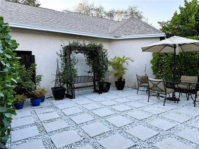a backyard of a house with table and chairs under an umbrella