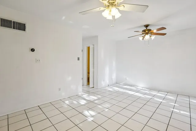 a view of an empty room with chandelier fan and fire place