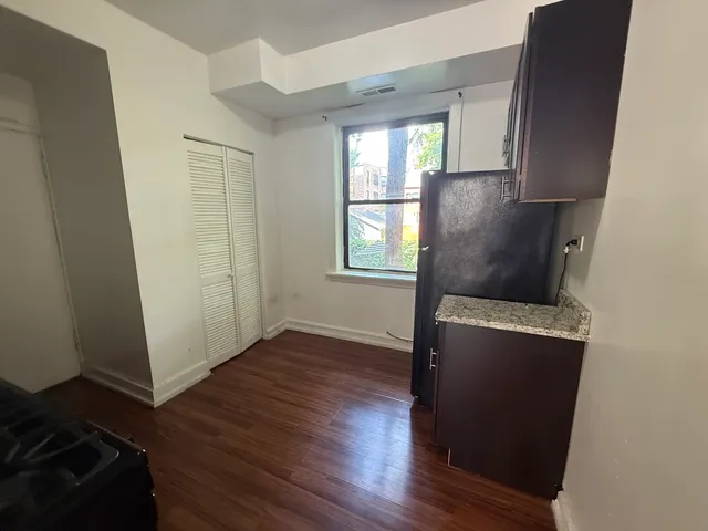 an empty room with wooden floor cabinet and windows