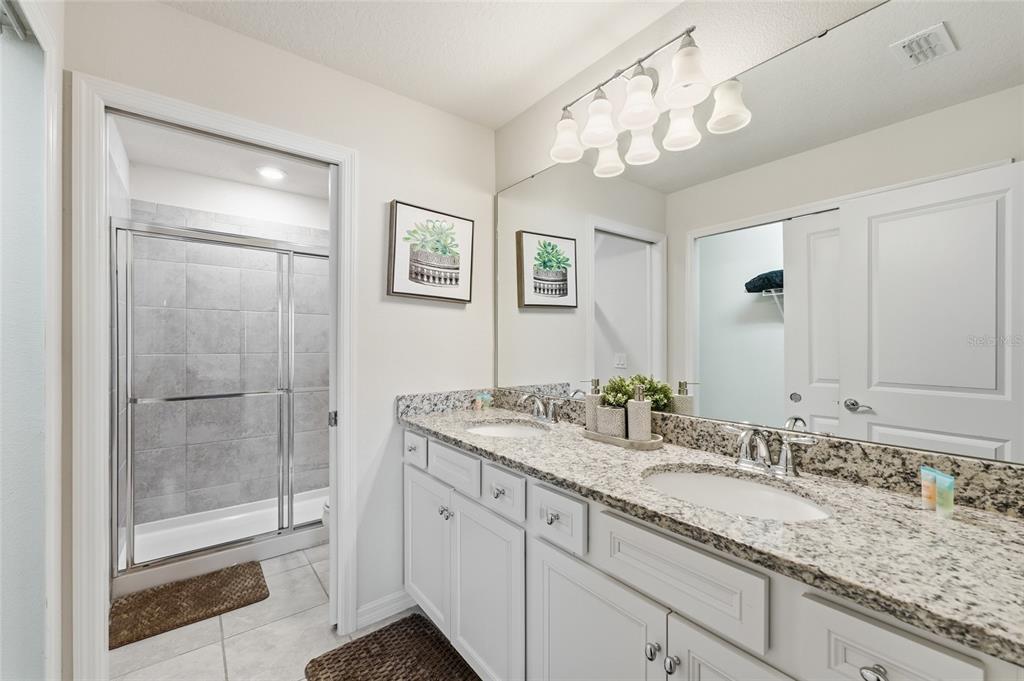 236 Jetty Way Davenport, FL 33897 - Photo 11 of 25 a bathroom with a granite countertop sink a mirror and a shower