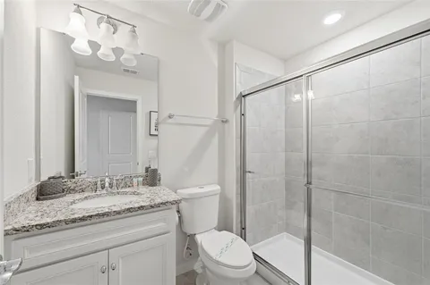 a bathroom with a granite countertop sink a toilet and shower