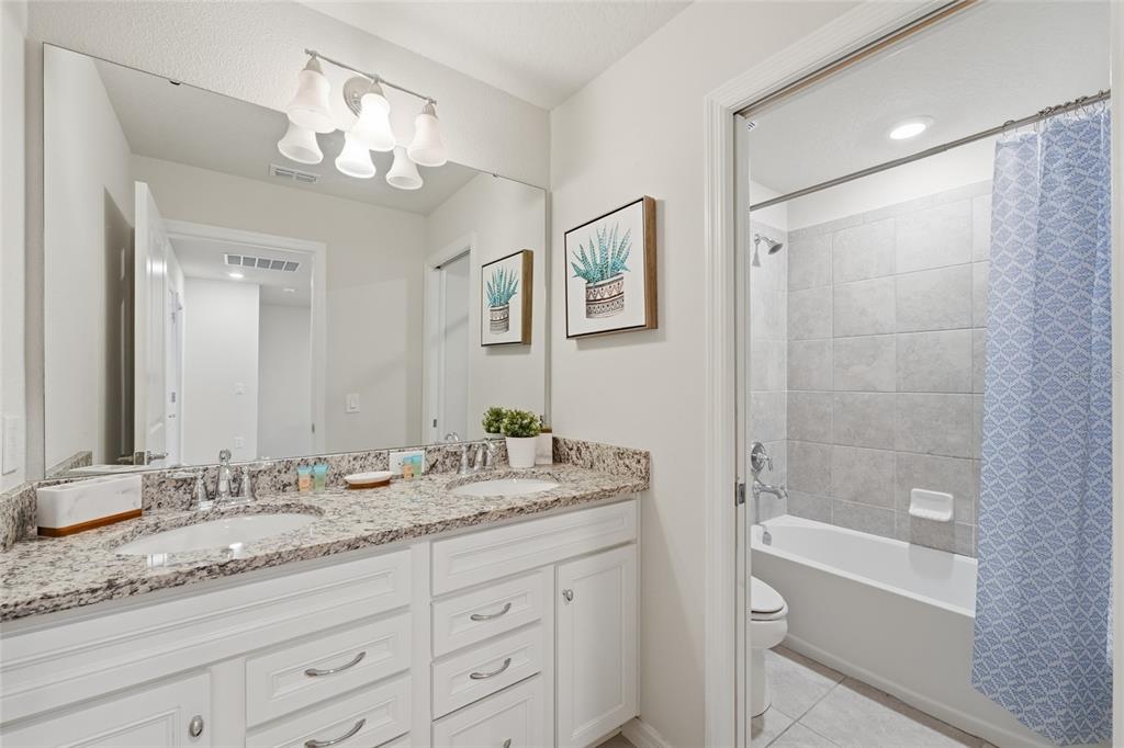 236 Jetty Way Davenport, FL 33897 - Photo 17 of 25 a bathroom with a granite countertop sink a mirror a shower and a bathtub
