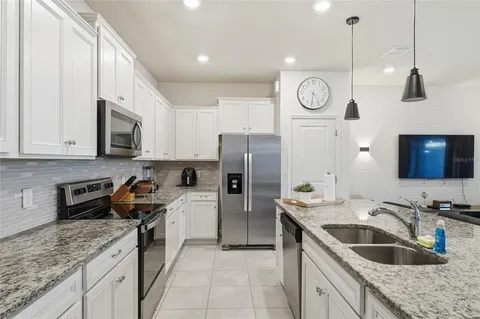 a kitchen with stainless steel appliances granite countertop a sink a stove a refrigerator a center island and cabinets