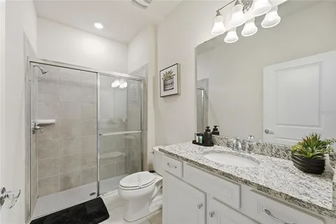 a bathroom with a granite countertop sink a toilet and a mirror