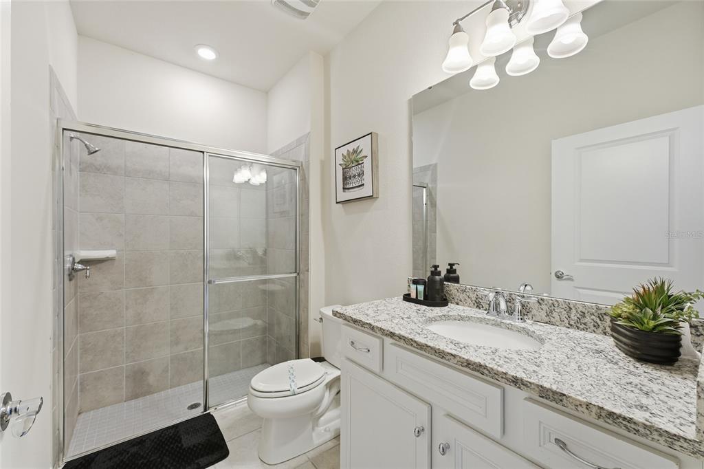 236 Jetty Way Davenport, FL 33897 - Photo 21 of 25 a bathroom with a granite countertop sink a toilet and a mirror