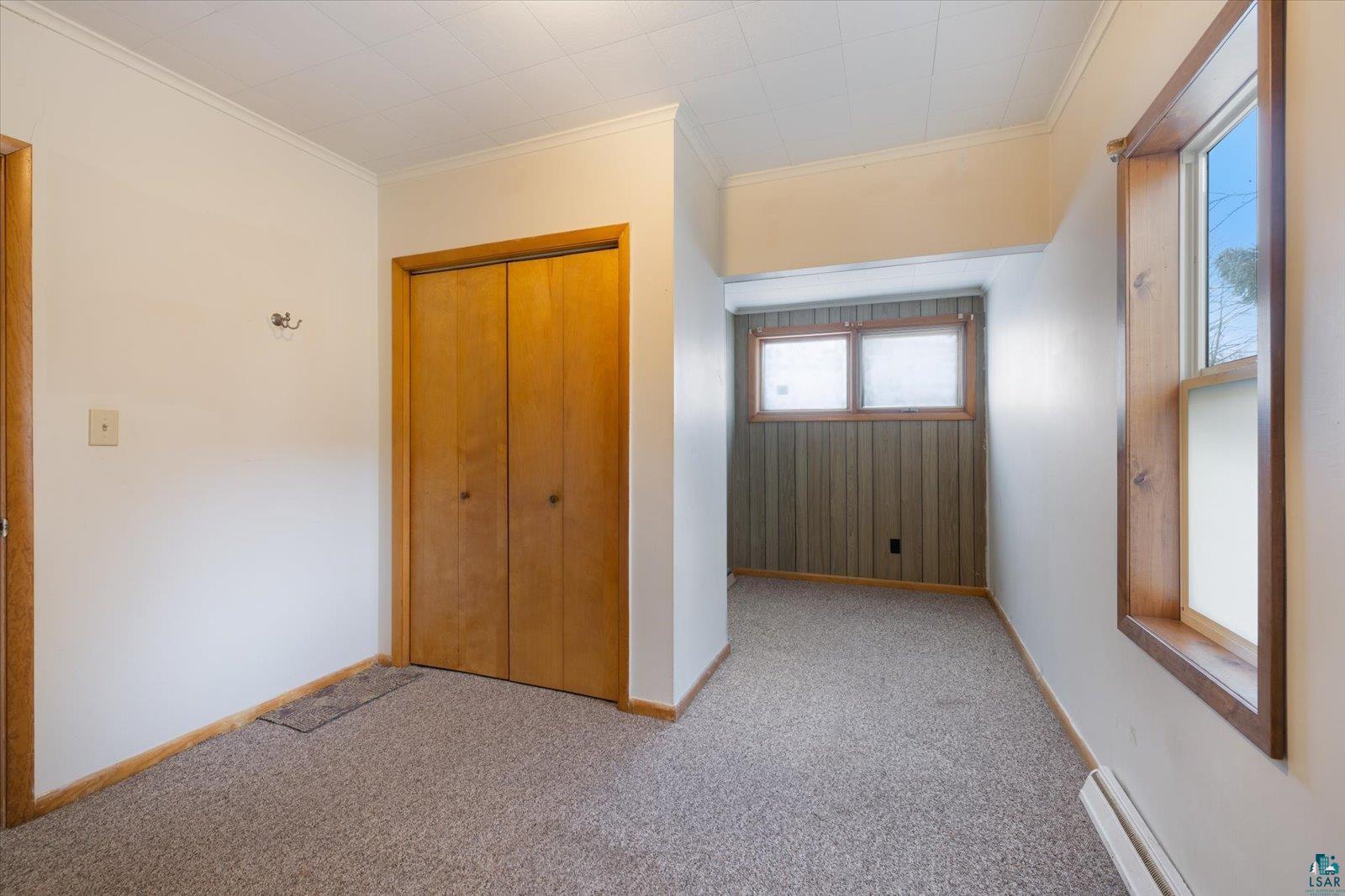 616 Summit Street Eveleth, MN 55734 - Photo 16 of 42 Unfurnished bedroom featuring light carpet, ornamental molding, a closet, and baseboard heating