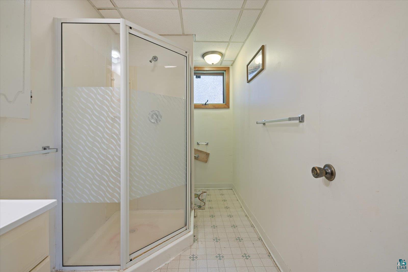 616 Summit Street Eveleth, MN 55734 - Photo 19 of 42 Bathroom with light flooring, a paneled ceiling, a stall shower, and vanity