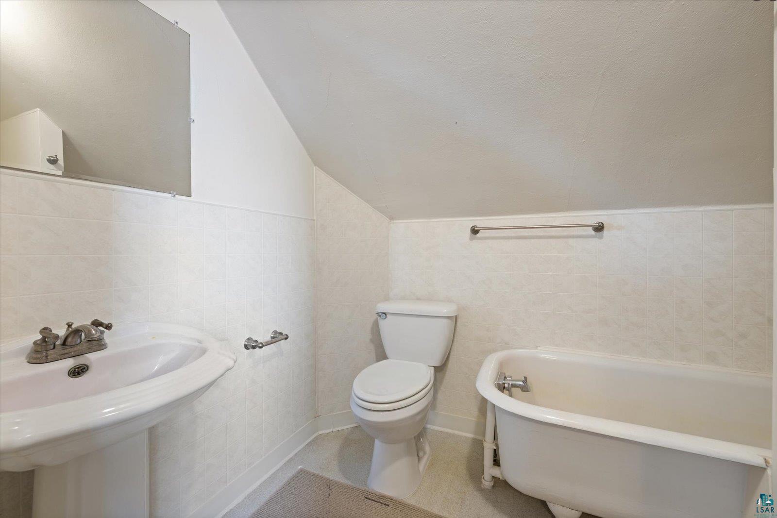 616 Summit Street Eveleth, MN 55734 - Photo 26 of 42 Bathroom with a soaking tub, vaulted ceiling, tile walls, and a wainscoted wall