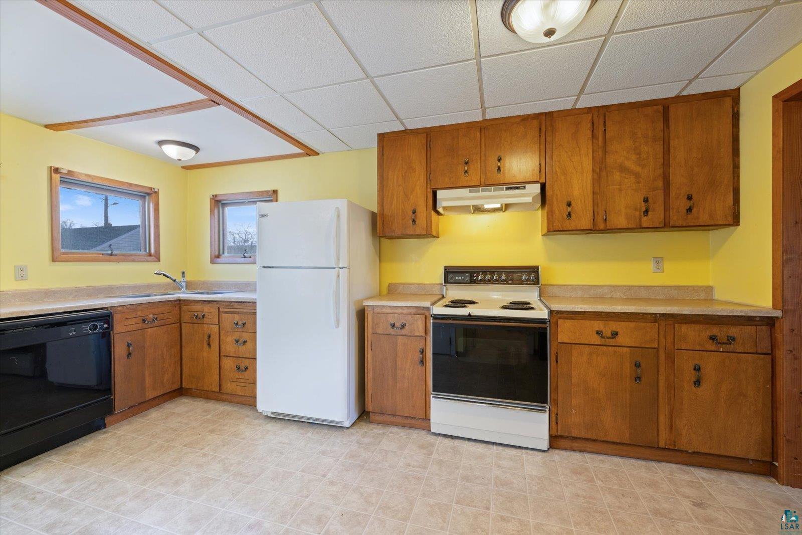 616 Summit Street Eveleth, MN 55734 - Photo 5 of 42 Kitchen with white appliances, wood finish cabinetry, light countertops, and a paneled ceiling