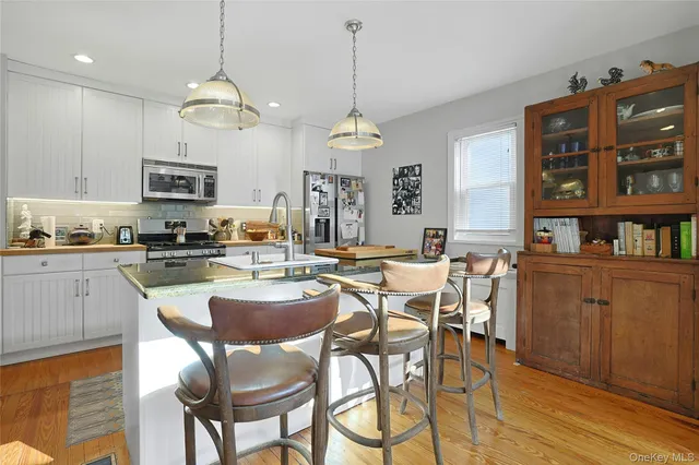 a kitchen with stainless steel appliances granite countertop a stove top oven a sink a dining table and chairs with wooden floor