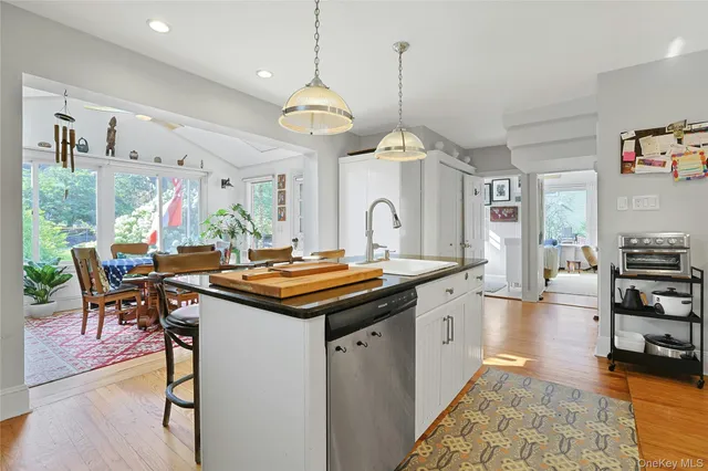 a kitchen with stainless steel appliances granite countertop a stove a island a dining table and chairs with wooden floor