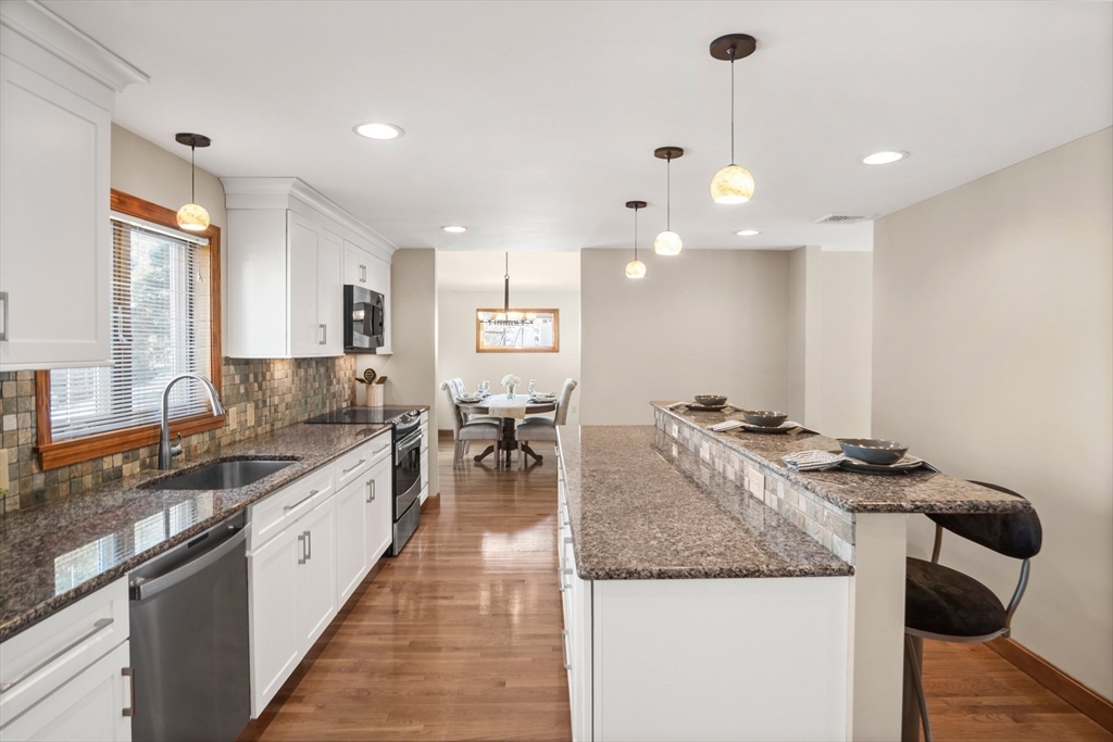 8 Grace Road Woburn, MA 01801 - Photo 8 of 37 a kitchen with granite countertop kitchen island a stove a sink a dining table and chairs