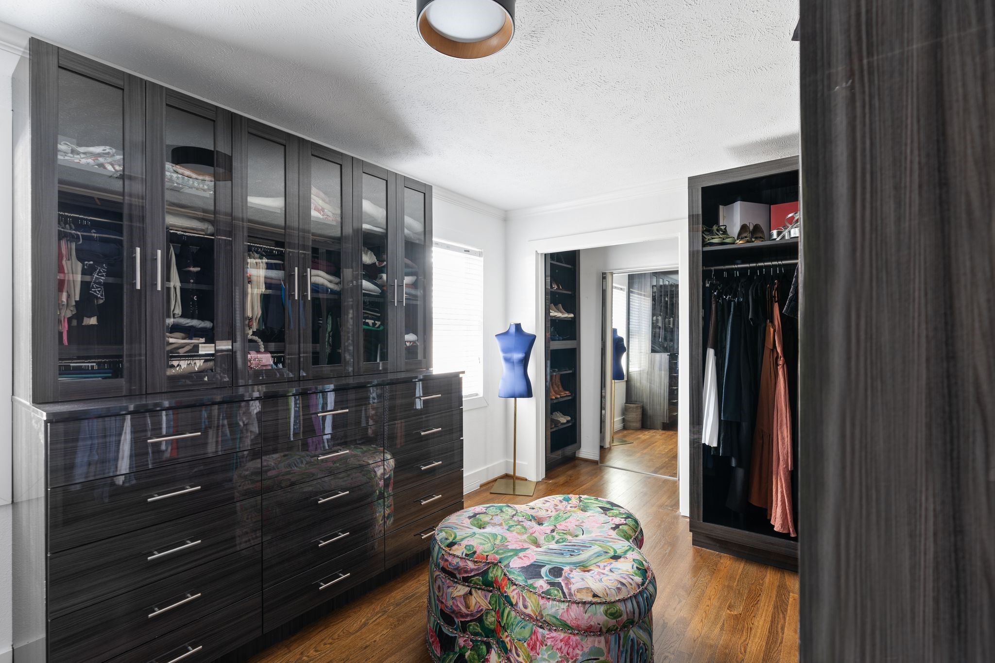 3914 Colquitt Street Houston, TX 77027 - Photo 12 of 36 This guest bedroom has been converted into a to die for custom closet with extensive built-ins and showroom style storage. It features a built-in dresser, clear display front cabinetry with integrated lighting, abundant hanging space for a sleek, organized setup, and generous shoe display storage. If needed the space could easily be converted back into a bedroom. In addition, there are two more closets for extra storage– one in the hallway and a walk-in closet located in the bathroom.