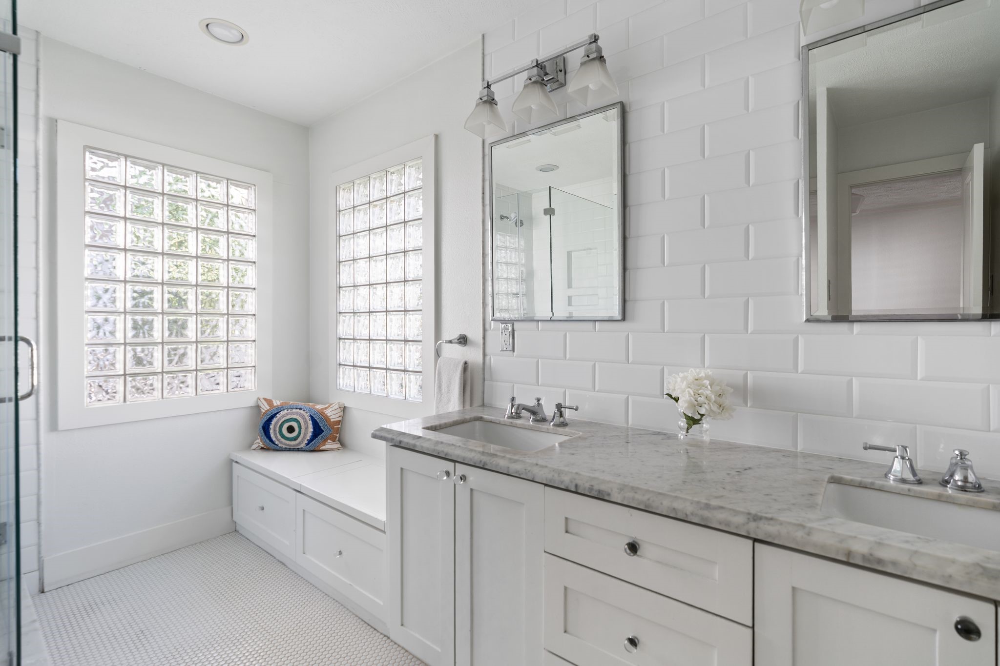 3914 Colquitt Street Houston, TX 77027 - Photo 13 of 36 The primary bathroom has a double sink vanity topped with marble countertops and complemented by a subway tile backsplash that extends all the way to the ceiling. Updated vanity lighting and large mirrors add a polished finish and the built-in bench with storage offers extra function.