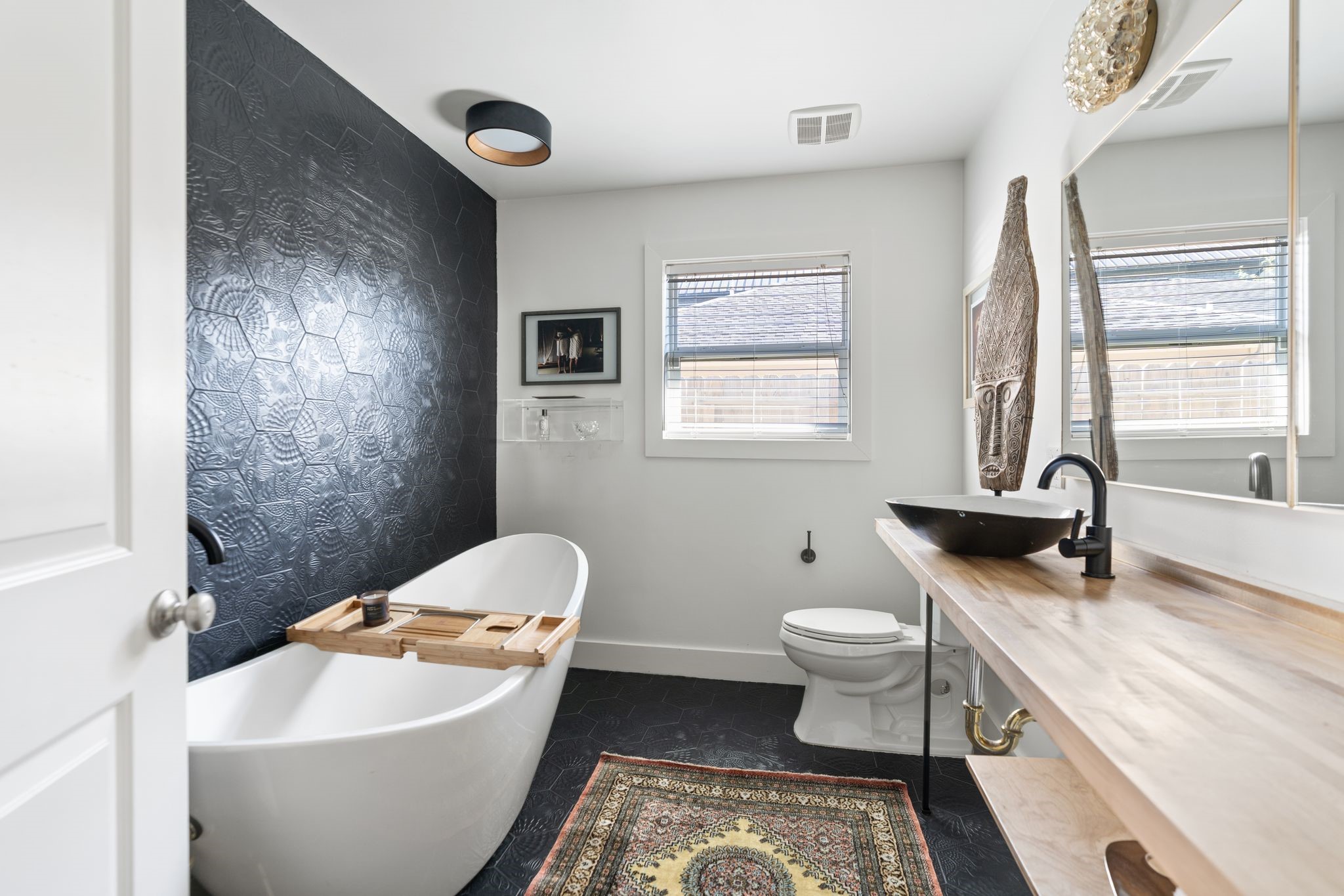 3914 Colquitt Street Houston, TX 77027 - Photo 17 of 36 The guest bathroom was renovated by the sellers in 2018 and has a curated, designer feel throughout. It features a warm wood countertop, decorative light fixtures, and a bold, decorative, hexagon tile flooring and wall detail for a standout look.
