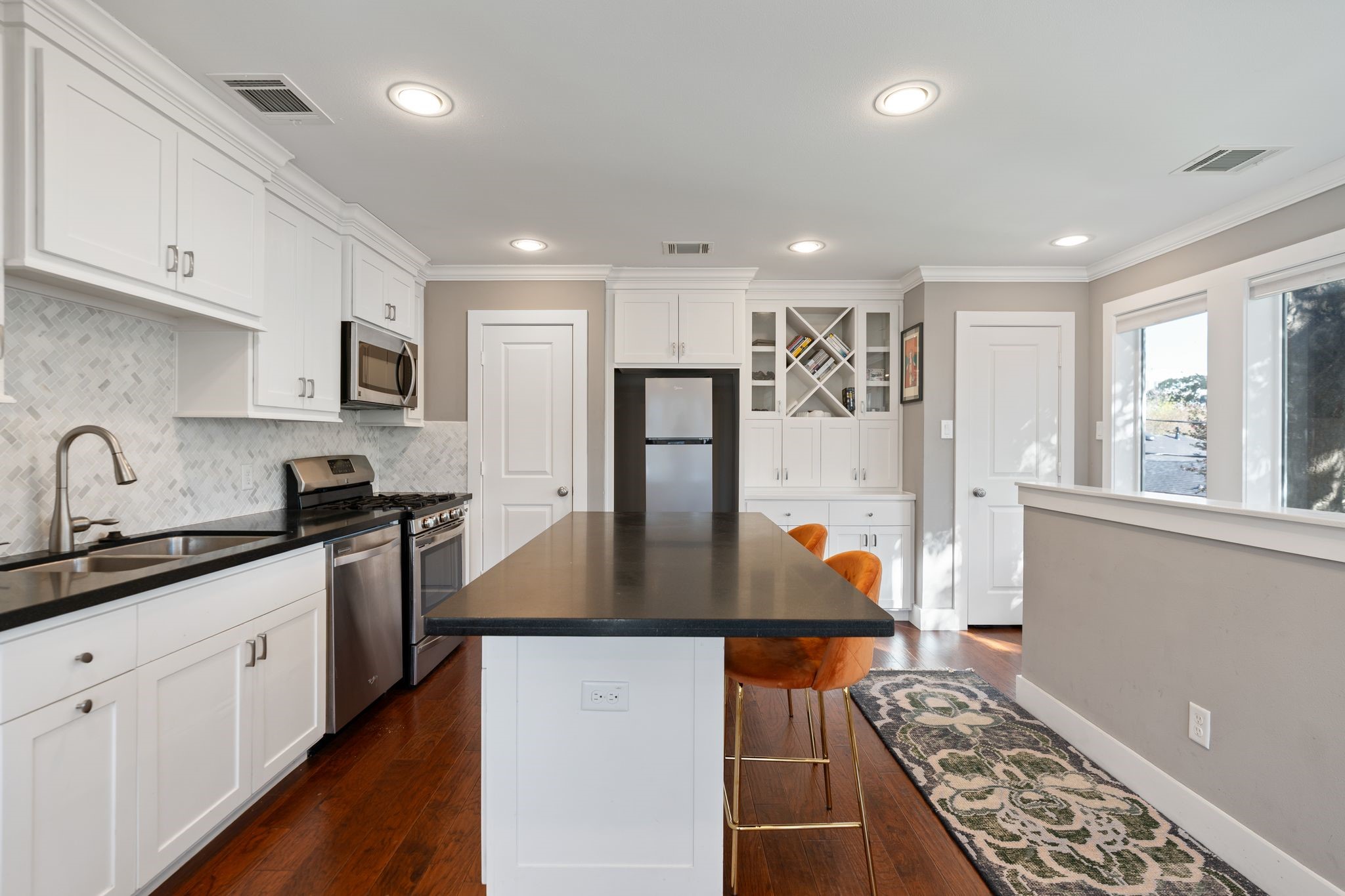 3914 Colquitt Street Houston, TX 77027 - Photo 21 of 36 Another view of the garage apartment kitchen highlights the extended Island and abundant cabinetry for everyday functionality. The marble herringbone backsplash adds a polished, designer touch and ties in the space together beautifully. Note the two closets for more storage!