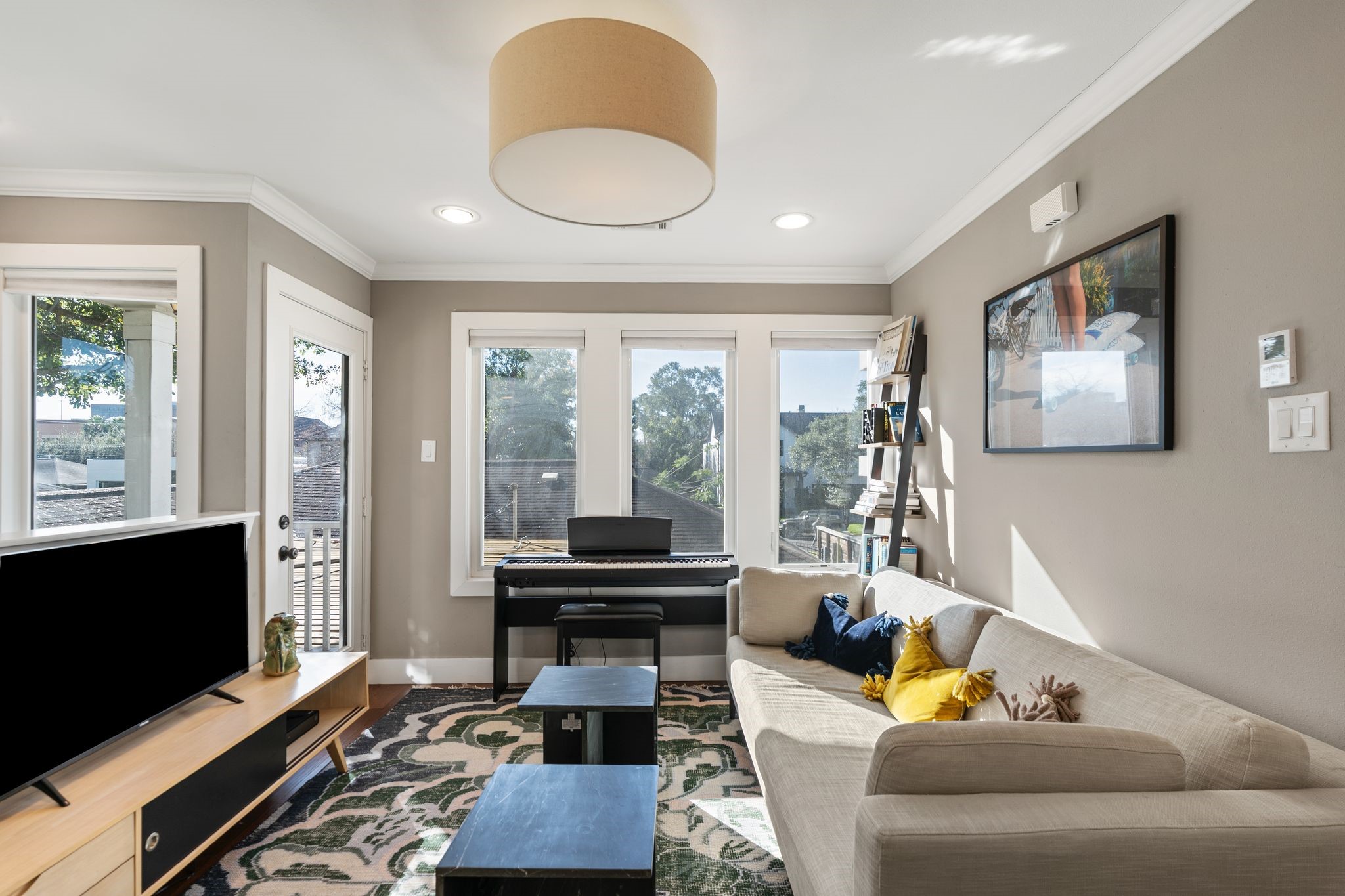 3914 Colquitt Street Houston, TX 77027 - Photo 23 of 36 The living area offers a comfortable, flexible space to lounge or work, with large windows that keep the room feeling open and inviting. The door leads out to a private balcony– perfect for fresh air, morning coffee, or enjoying the treetop views.