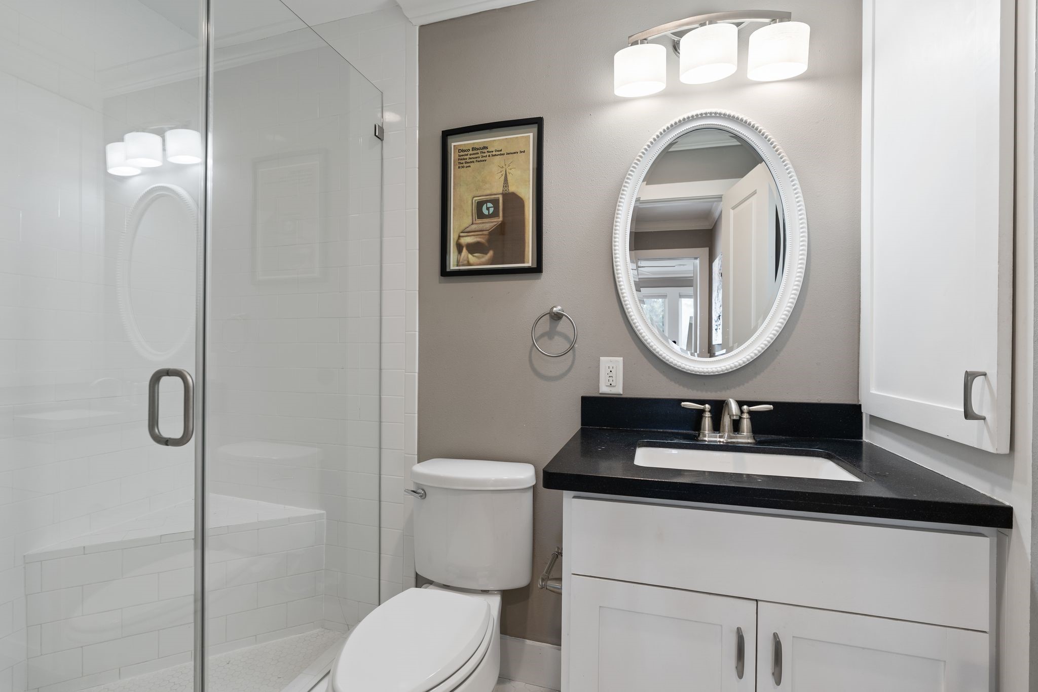 3914 Colquitt Street Houston, TX 77027 - Photo 26 of 36 The bathroom features a clean, modern setup with a glass-enclosed shower and updated vanity. A framed mirror and contemporary light fixture finish the space with a polished look.