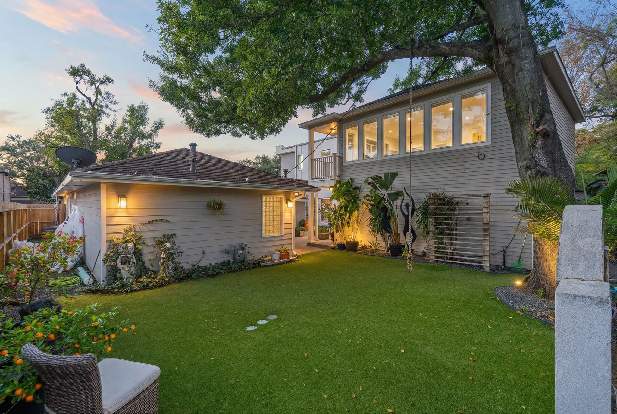 3914 Colquitt Street Houston, TX 77027 - Photo 33 of 36 The twilight view captures the warm exterior lighting and the scale of the backyard creating a cozy atmosphere as the sun goes down. It's the kind of space that feels perfect for hosting– string lights on, music playing, and everyone enjoying the outdoors.