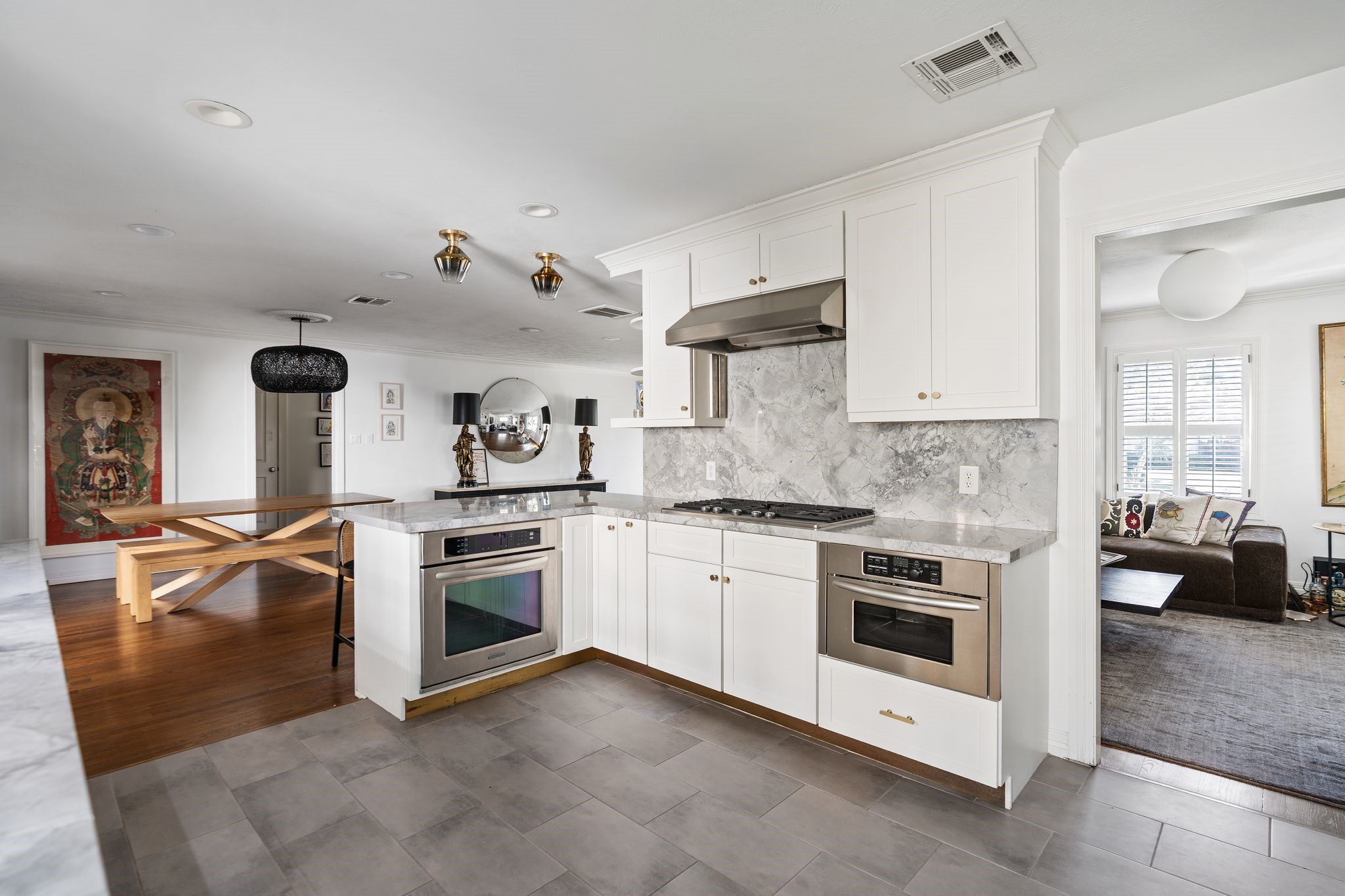 3914 Colquitt Street Houston, TX 77027 - Photo 8 of 36 The updated kitchen offers a functional open layout with great sightlines into the adjacent dining area. renovated in 2018 and 2020, it features quartz countertops, brass hardware, updated tile flooring, and two decorative light fixtures over the breakfast bar.