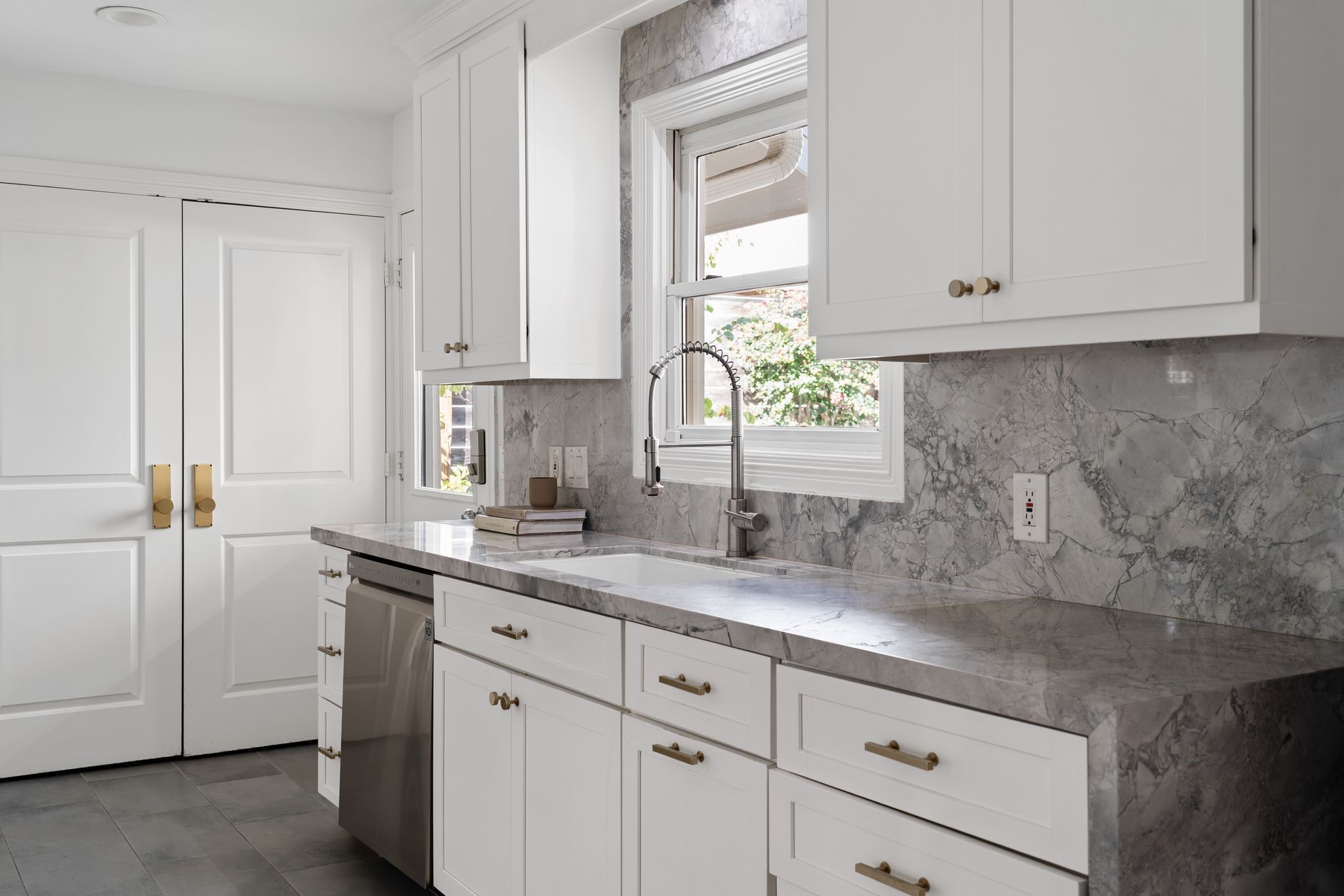 3914 Colquitt Street Houston, TX 77027 - Photo 9 of 36 This side of the kitchen includes an LG dishwasher and convenient sink area with extensive counter space. The window above the sink overlooks the outdoor living space, perfect for keeping an eye on the backyard. The door to the left leads out to the driveway perfect for unloading groceries.