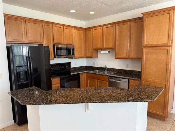 a kitchen with stainless steel appliances granite countertop a refrigerator a stove a sink and a microwave