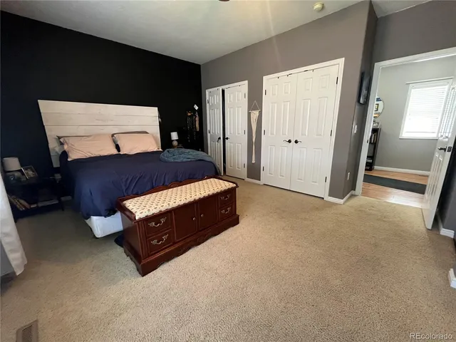 a spacious bedroom with a bed and a lamp