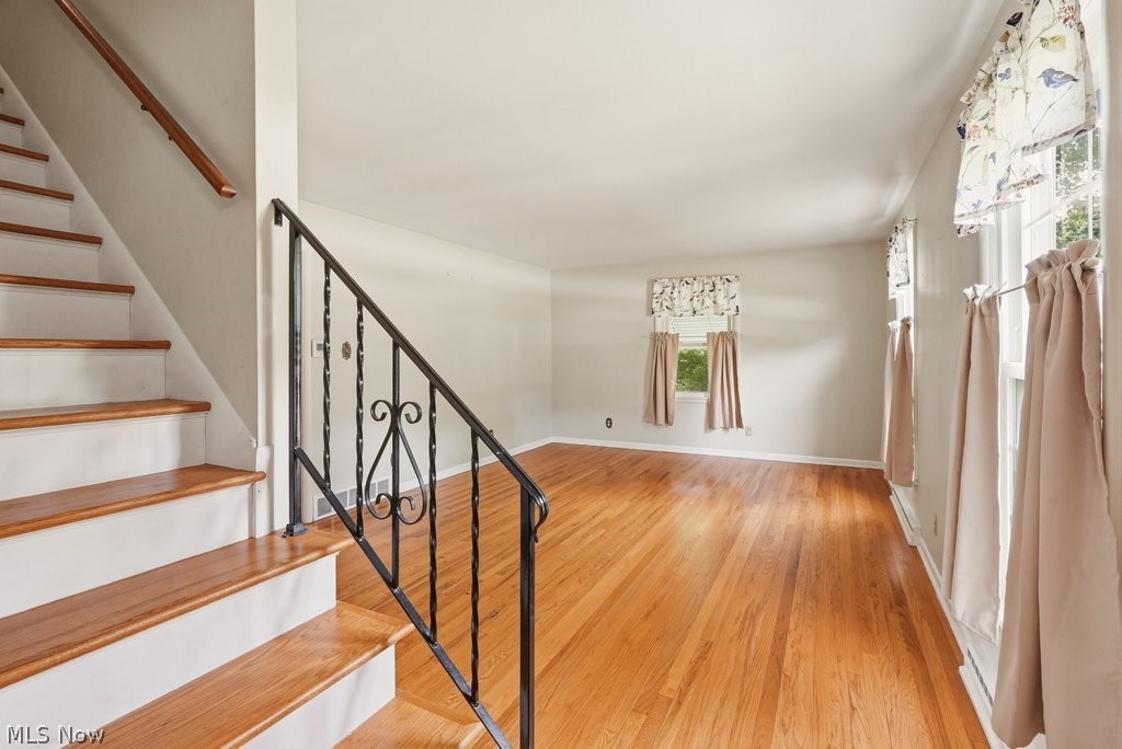 161 Pinehurst Road Munroe Falls, OH 44262 - Photo 4 of 40 Refinished wood flooring in a brightly lit room featuring a staircase with a wrought iron railing and wood handrail