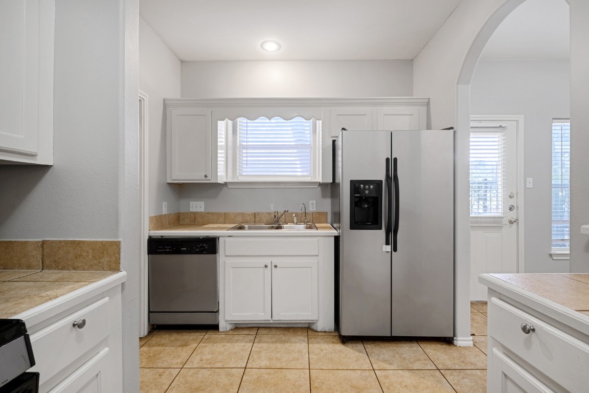 2906 Pearl Street, Unit C Austin, TX 78705 - Photo 9 of 25 Kitchen featuring white cabinetry, appliances with stainless steel finishes, arched walkways, and tile countertops