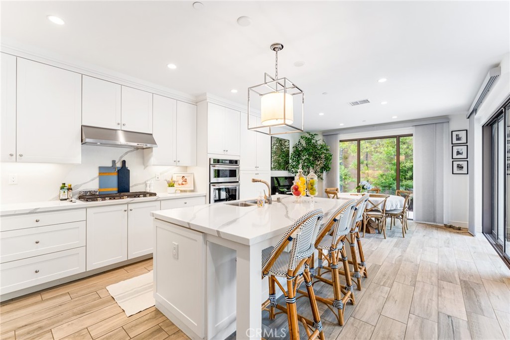 218 Oceano Irvine, CA 92602 - Photo 32 of 56 a open kitchen with stainless steel appliances granite countertop a stove a refrigerator a kitchen island a sink white cabinets and couches with wooden floor