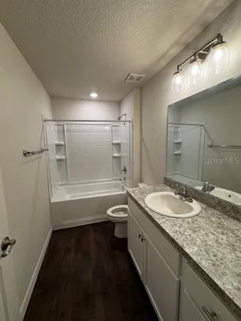a bathroom with a granite countertop sink a toilet a mirror and shower