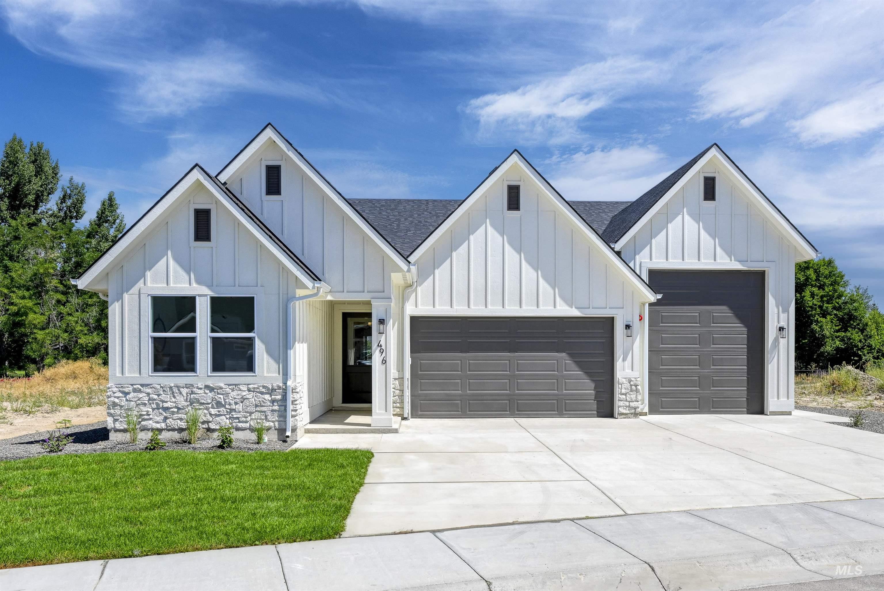 Modern farmhouse featuring stone siding, board and batten siding, driveway, and a garage