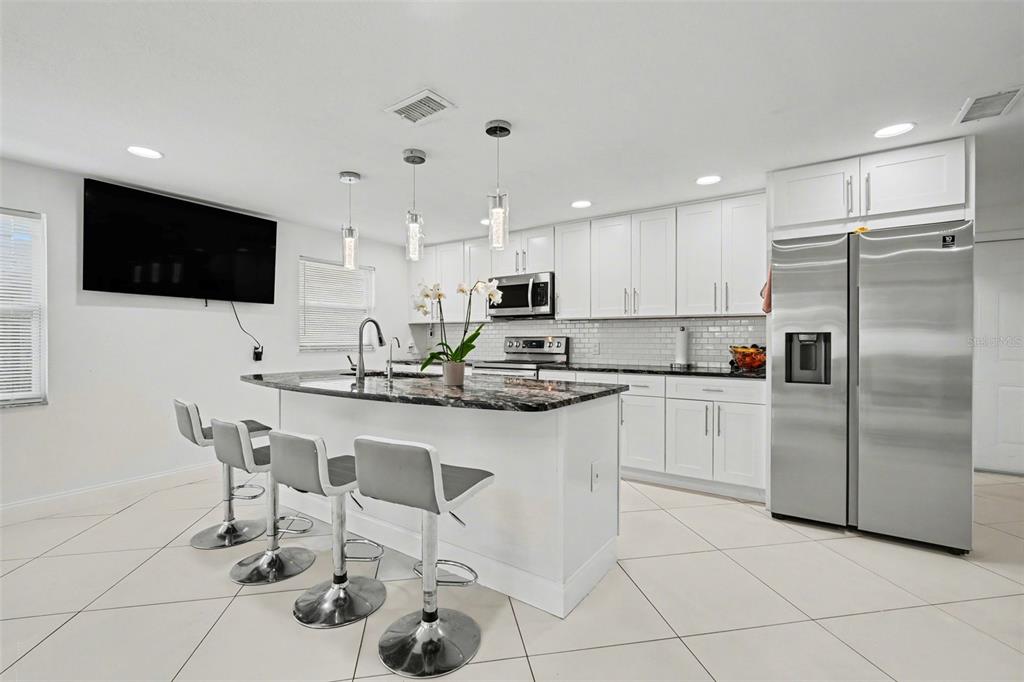11828 Bingham Drive Port Richey, FL 34668 - Photo 14 of 32 a kitchen with stainless steel appliances granite countertop a sink a stove a microwave a refrigerator and cabinets