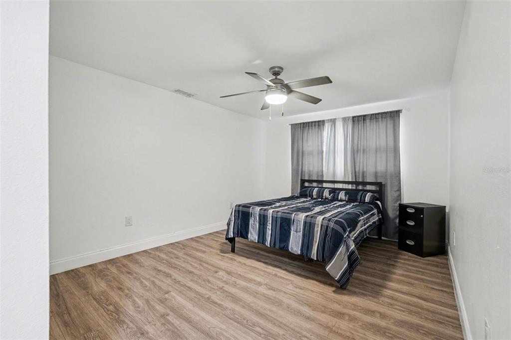 11828 Bingham Drive Port Richey, FL 34668 - Photo 19 of 32 a spacious bedroom with a bed and a ceiling fan